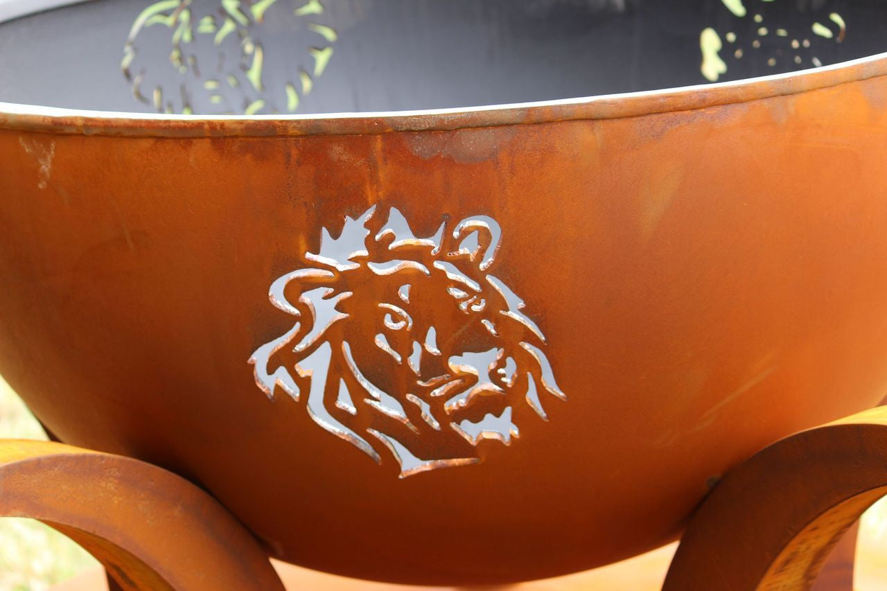 Rust-colored metal fire pit with a lion emblem on a blurred background