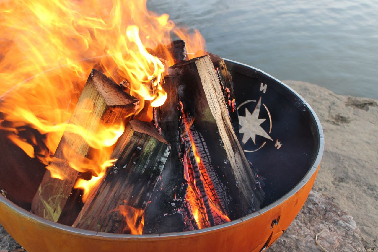 Fire pit with burning wood by a body of water