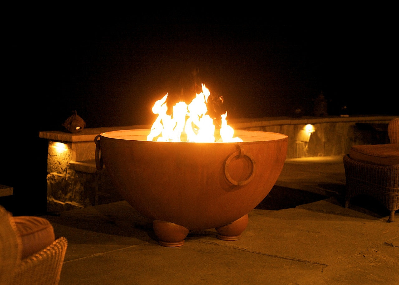 Fire pit with flames glowing in an outdoor setting at night.
