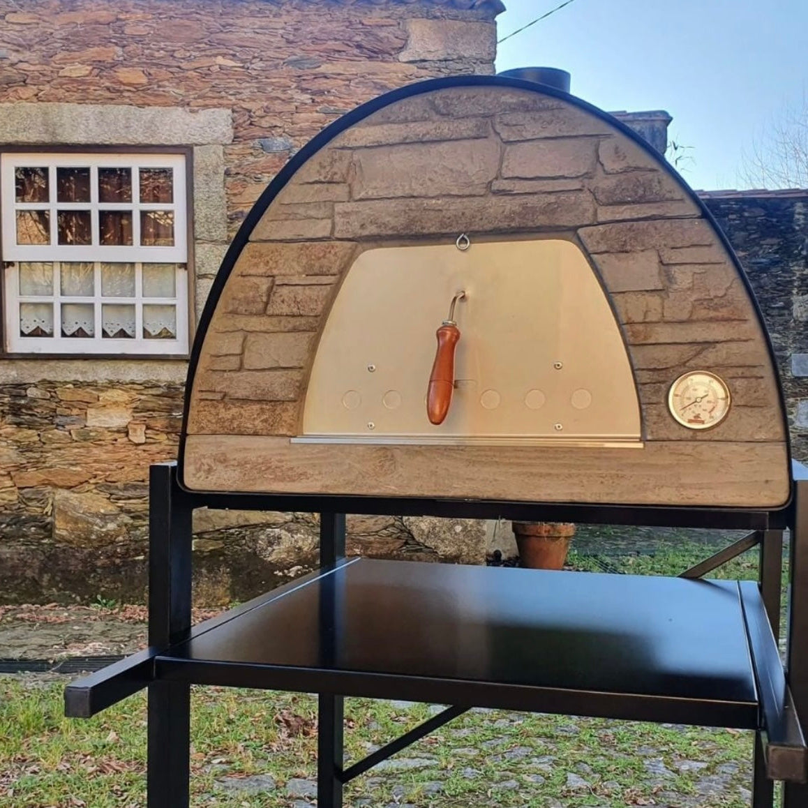 Wooden pizza oven with a stone wall and window in the background