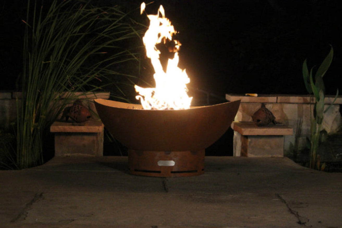 Rust-colored fire pit bowl with flames burning at night,