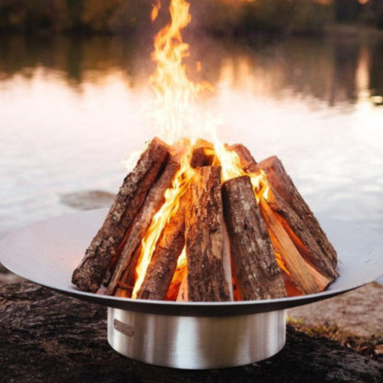 Fire pit with burning wood by a body of water