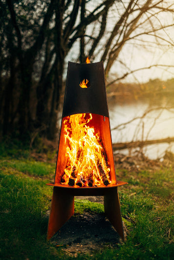 Artistic scullpture of Fire pit tower with flames burning in a natural setting